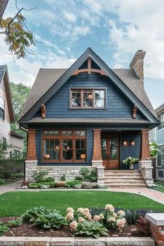 a blue house with two story windows and landscaping around the front yard area is surrounded by greenery