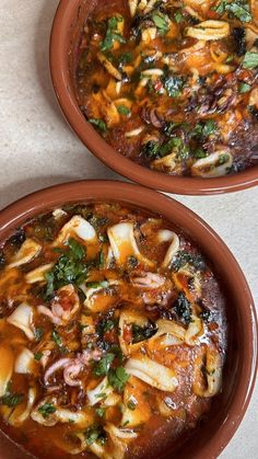 two brown bowls filled with food on top of a table