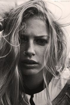 a black and white photo of a woman with hair blowing in the wind