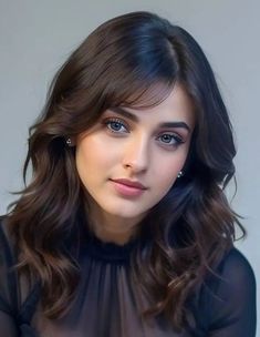 a woman with long dark hair wearing a black top and looking at the camera while sitting down