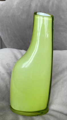 a green vase sitting on top of a bed