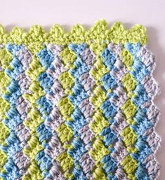 a crocheted dishcloth with blue, green and white squares on the bottom