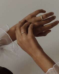 two hands reaching up to each other with wedding rings on their fingers and veils around them