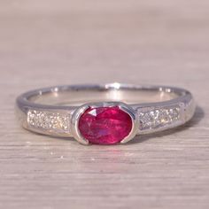 a close up of a ring with a pink stone in the middle and white diamonds around it