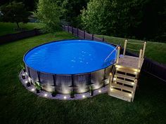 an above ground swimming pool with lights around it and steps leading up to the bottom