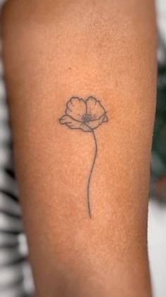 a single flower tattoo on the right arm is shown in black and grey ink,