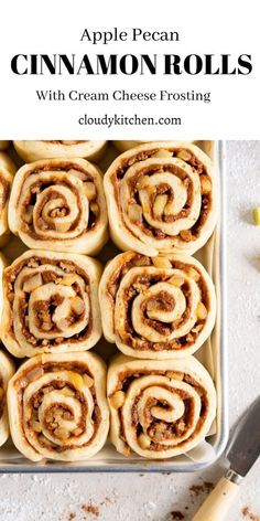 apple pecan cinnamon rolls with cream cheese frosting in a baking pan on a white surface