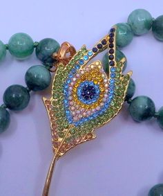 a green beaded necklace with an evil eye brooch on it and some beads