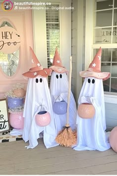 three white ghost statues with brooms and hats on their heads in front of a door