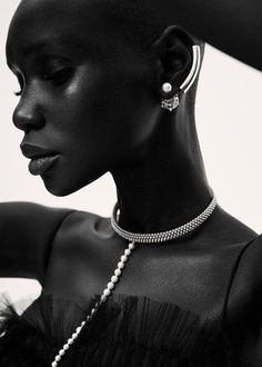 a woman in a black dress with pearls on her neck and necklaces around her neck