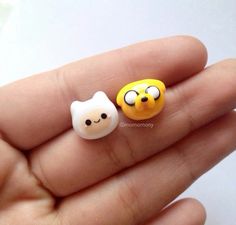 two small yellow and white faces are in someone's hand