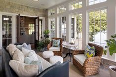 a living room filled with lots of furniture next to a window covered in glass doors