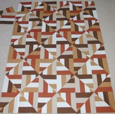 an orange and brown quilt is laying on the floor