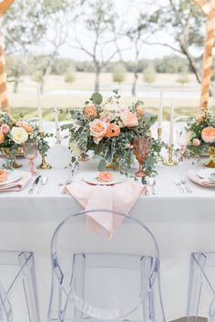 the table is set with candles, plates and pink napkins on top of it