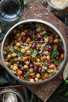 a bowl filled with beans and rice on top of a wooden cutting board next to other dishes