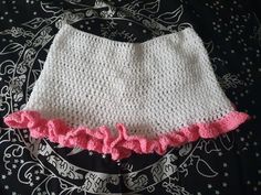 a crocheted skirt with pink ruffles on the bottom is laying on a bed