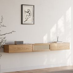 a white wall with a wooden shelf and plant in the corner next to an art piece