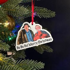 a christmas ornament hanging from the side of a tree with an image of two men on it