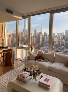 a living room filled with furniture and large windows overlooking the cityscape in the distance