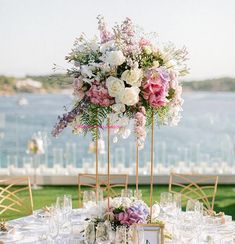 the table is set with flowers and place settings for an elegant wedding reception at the water's edge