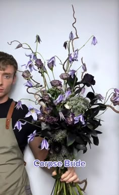 a man holding a bouquet of purple flowers