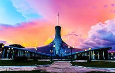 the building has many lights on it at sunset or dawn in front of colorful clouds