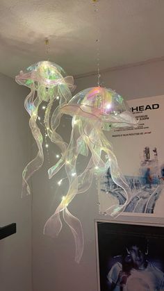 a light up jellyfish hanging from the ceiling in a room with pictures on it