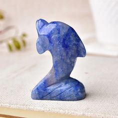 a small blue cat figurine sitting on top of a white cloth covered table