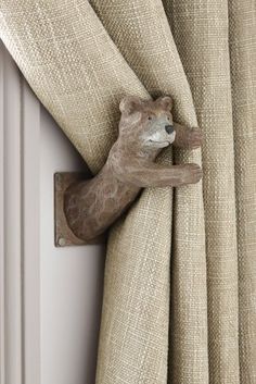 a bear figurine hanging on the side of a curtain