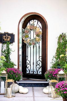 the front door is decorated with purple flowers and greenery, while gold lanterns are on either side