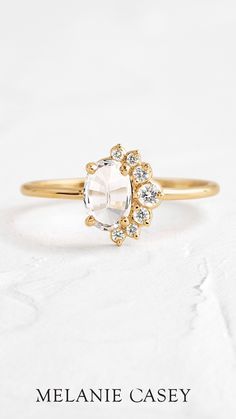 a gold engagement ring with an oval cut stone surrounded by small white and clear stones