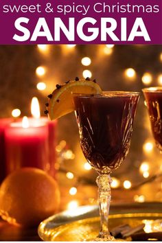 two glasses filled with liquid sitting on top of a table next to oranges and candles