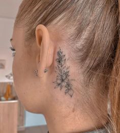 a woman with a flower tattoo on her left side behind the ear is looking down