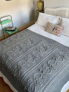 a bed with a blanket and pillows on top of it next to a green chair