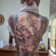 the back of a woman's body with tattoos on it