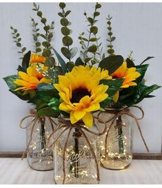 two mason jars with sunflowers and greenery in them