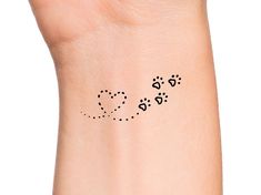 a small wrist tattoo with three paw prints on it's left arm and the word love written in black ink