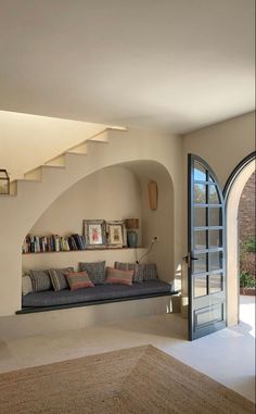 a living room filled with furniture and a book shelf on top of a stair case