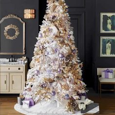 a white christmas tree with purple and gold decorations