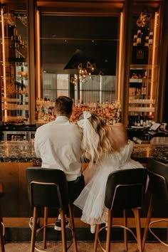 a man and woman sitting at a bar with their backs to each other in front of the bar