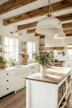 a large kitchen with white cabinets and wooden beams on the ceiling is decorated with greenery