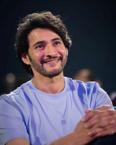 a man sitting down and smiling at the camera