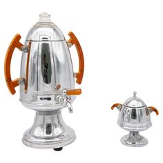 a silver coffee pot with an orange handle and wooden handles on the top, next to it