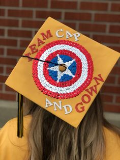 a person wearing a graduation cap with the captain's shield painted on it and words that read beamcap and crown