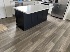 a kitchen with an island in the middle and stainless steel appliances on the other side