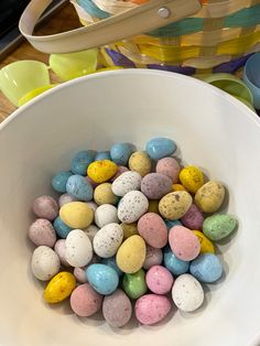 a white bowl filled with lots of colorful candy eggs