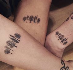 two people with matching tattoos on their legs, one has trees and the other has words