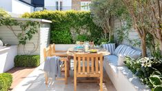 an outdoor dining area with wooden furniture and potted plants on the side of it