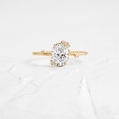 a yellow gold engagement ring with an oval cut diamond in the center, on a white background