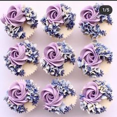 twelve cupcakes with purple frosting and blue flowers on them are arranged in rows